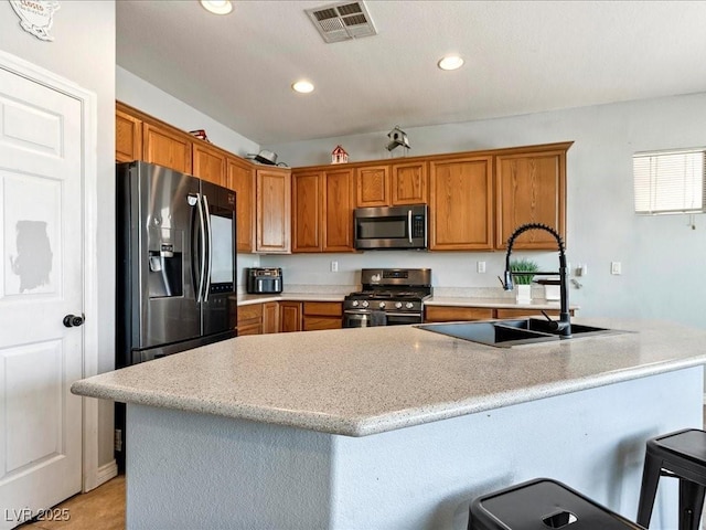 3040 Balcones Fault Ave, North Las Vegas, NV 89081 - kitchen with appliances with stainless steel finishes, a sink, recessed lighting, brown cabinets, and a kitchen bar