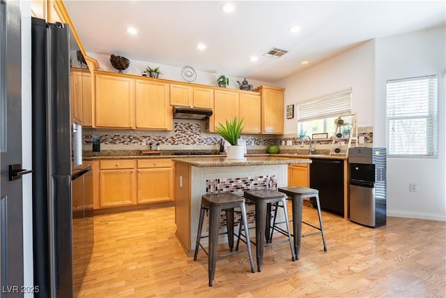 11134 Casala Ct, Las Vegas, NV 89141 - kitchen with black appliances, under cabinet range hood, light wood finished floors, decorative backsplash, and light brown cabinets