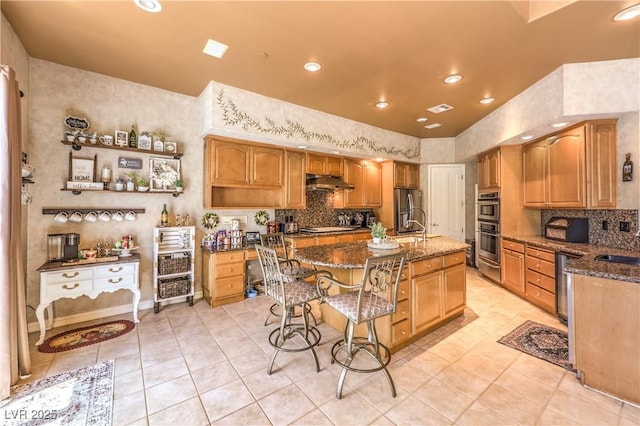 27 Via Paradiso St, Henderson, NV 89011 - kitchen featuring stainless steel appliances, under cabinet range hood, dark stone counters, light tile patterned flooring, and recessed lighting