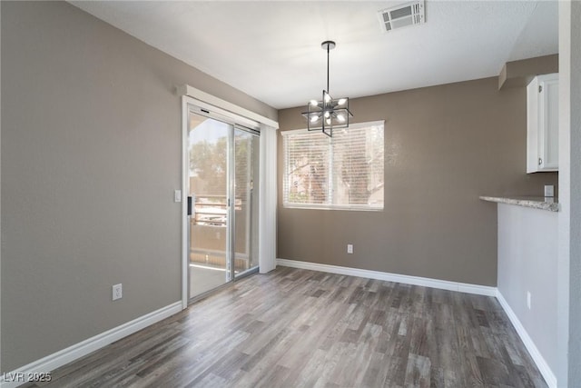 6873 Tamarus St Unit 201, Las Vegas, NV 89119 - unfurnished dining area with a chandelier, wood finished floors, and baseboards