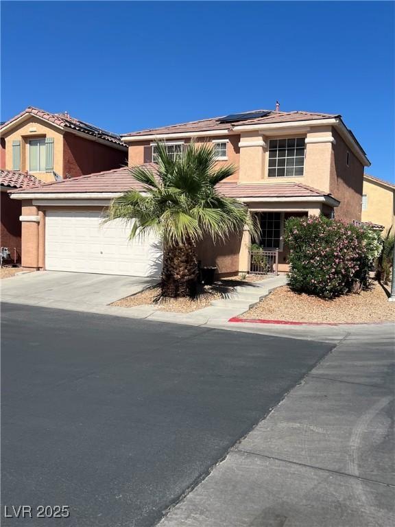 5456 Raccoon Valley Ln, Las Vegas, NV 89122 - view of front of house with driveway, solar panels, stucco siding, an attached garage, and a tiled roof