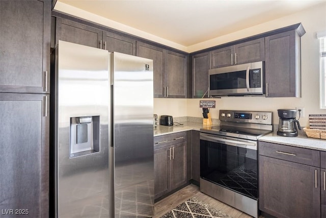 2629 Mocha Pearl Ct, North Las Vegas, NV 89086 - kitchen featuring stainless steel appliances, dark brown cabinetry, light wood-type flooring, and light stone counters