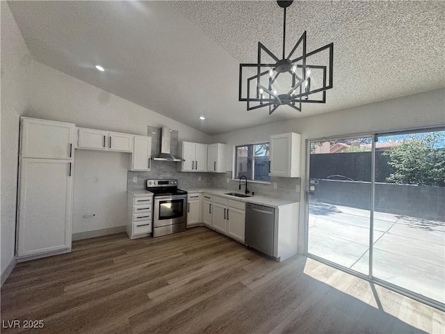 3920 Aspencrest Dr, Las Vegas, NV 89108 - kitchen featuring stainless steel appliances, wall chimney range hood, a sink, dark wood-style flooring, and vaulted ceiling