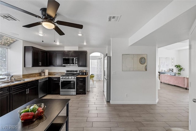 9428 Sierra Summit Ave, Las Vegas, NV 89134 - kitchen with stainless steel appliances, a sink, arched walkways, a ceiling fan, and baseboards