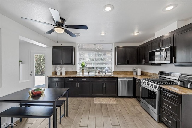 9428 Sierra Summit Ave, Las Vegas, NV 89134 - kitchen featuring appliances with stainless steel finishes, a sink, a ceiling fan, light wood-type flooring, and dark cabinets