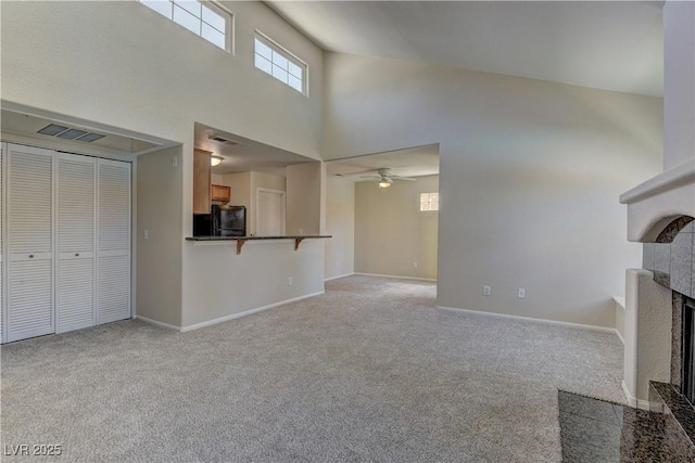 3145 E Flamingo Rd Unit 2080, Las Vegas, NV 89121 - unfurnished living room featuring a towering ceiling, light colored carpet, a fireplace, baseboards, and a ceiling fan