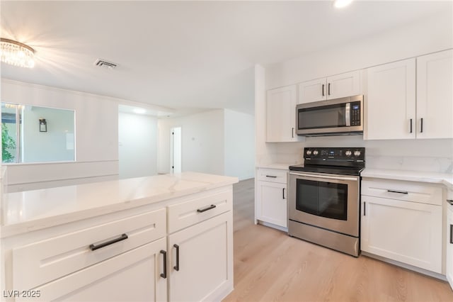 4301 Fortune Ave, Las Vegas, NV 89107 - kitchen featuring stainless steel appliances, white cabinetry, light wood-style floors, light stone countertops, and recessed lighting