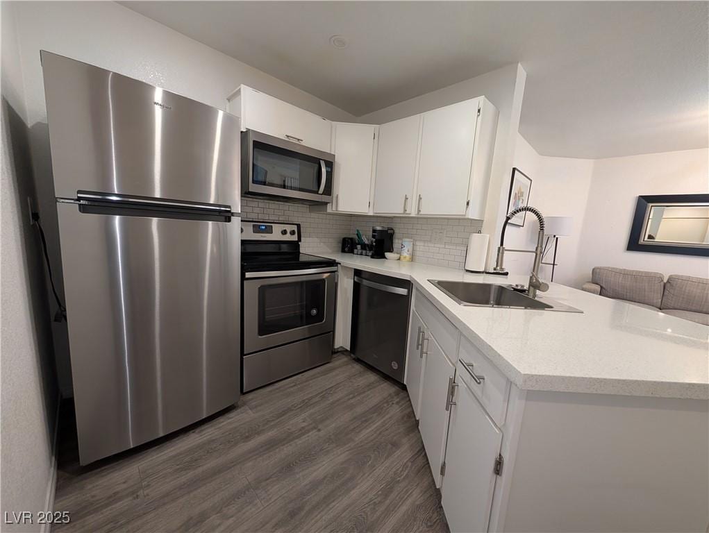 460 Elm Dr Unit 103, Las Vegas, NV 89169 - kitchen featuring appliances with stainless steel finishes, a sink, dark wood-type flooring, a peninsula, and white cabinets
