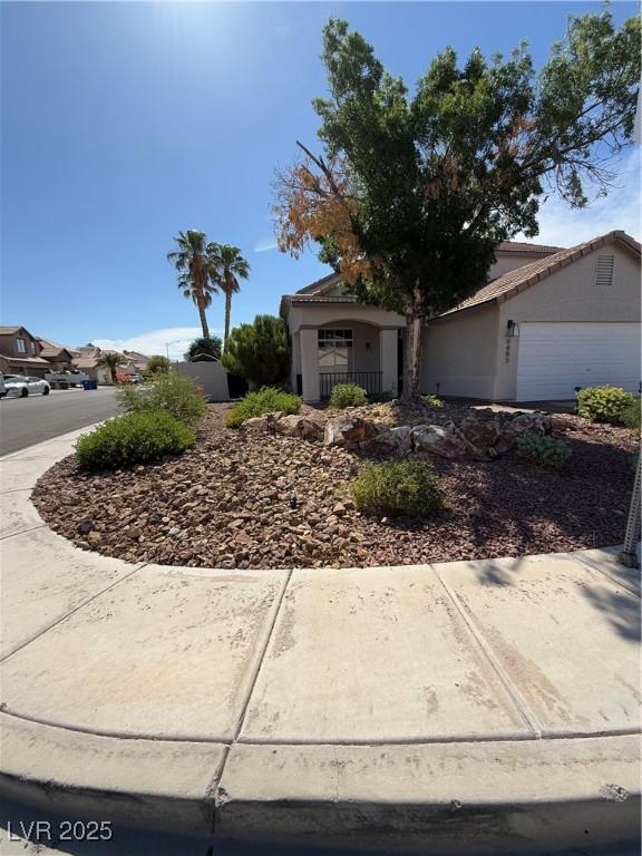 9485 Supernova Ct, Las Vegas, NV 89123 - view of property hidden behind natural elements featuring an attached garage and stucco siding