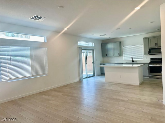 10376 Joaquin Fire St, Las Vegas, NV 89141 - kitchen featuring stainless steel appliances, a sink, light countertops, light wood-type flooring, and a kitchen island