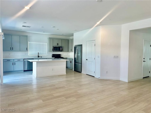 10376 Joaquin Fire St, Las Vegas, NV 89141 - kitchen featuring appliances with stainless steel finishes, a sink, light countertops, a kitchen island, and light wood-type flooring