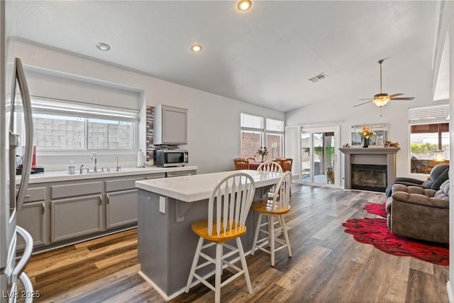 5317 Marietta Ave, Las Vegas, NV 89108 - kitchen with gray cabinetry, stainless steel appliances, wood finished floors, tile countertops, and a kitchen bar