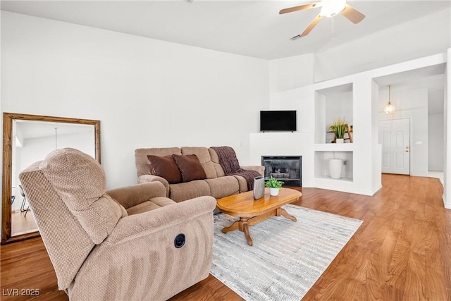 5704 Owl Butte Ct, Las Vegas, NV 89149 - living area featuring ceiling fan, built in shelves, wood finished floors, and a glass covered fireplace