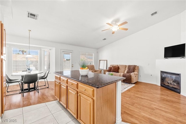 5704 Owl Butte Ct, Las Vegas, NV 89149 - kitchen with lofted ceiling, ceiling fan, dark stone counters, light wood-type flooring, and a kitchen island