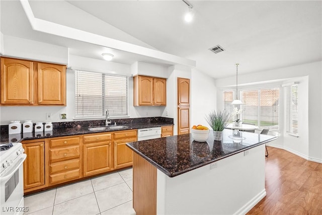 5704 Owl Butte Ct, Las Vegas, NV 89149 - kitchen with a sink, white appliances, vaulted ceiling, dark stone counters, and hanging light fixtures