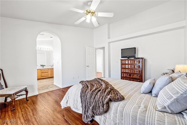 5704 Owl Butte Ct, Las Vegas, NV 89149 - bedroom featuring light wood-type flooring, arched walkways, ceiling fan, baseboards, and connected bathroom