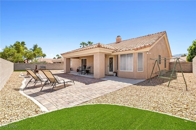 5704 Owl Butte Ct, Las Vegas, NV 89149 - rear view of house featuring a chimney, a tiled roof, stucco siding, a fenced backyard, and a patio area