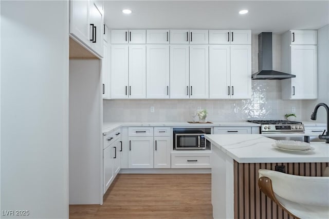 1136 Casady Hollow Ave, Henderson, NV 89012 - kitchen featuring wall chimney exhaust hood, stainless steel microwave, backsplash, white cabinetry, and recessed lighting