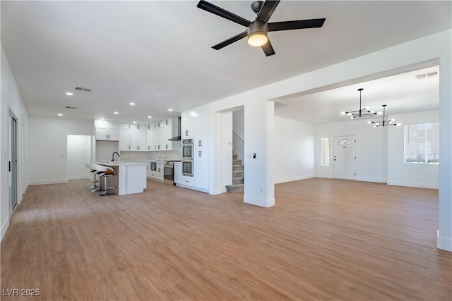 1136 Casady Hollow Ave, Henderson, NV 89012 - unfurnished living room with stairs, baseboards, a chandelier, light wood-style flooring, and recessed lighting