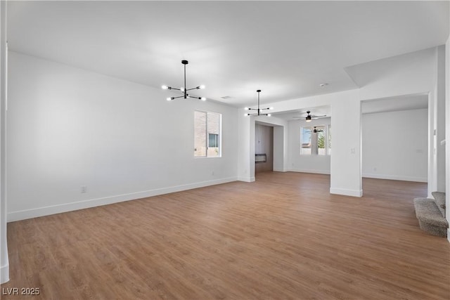 1136 Casady Hollow Ave, Henderson, NV 89012 - unfurnished living room with a chandelier, light wood-style floors, baseboards, and ceiling fan