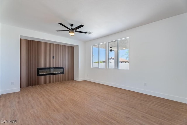 1136 Casady Hollow Ave, Henderson, NV 89012 - unfurnished living room featuring a ceiling fan, a glass covered fireplace, wood finished floors, and baseboards