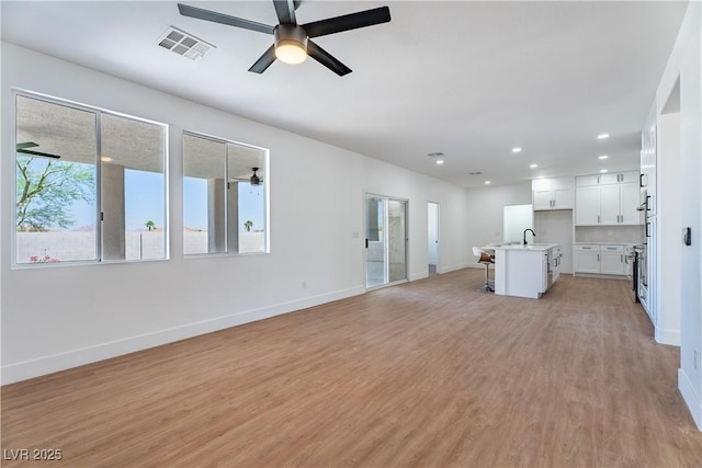 1136 Casady Hollow Ave, Henderson, NV 89012 - unfurnished living room featuring a ceiling fan, baseboards, a sink, light wood-style floors, and recessed lighting