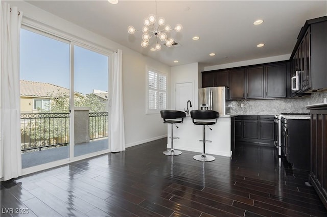 1185 Via Dimartini, Henderson, NV 89052 - kitchen featuring appliances with stainless steel finishes, tasteful backsplash, a breakfast bar, baseboards, and dark wood-type flooring