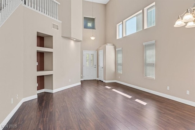 2864 Kinknockie Way, Henderson, NV 89044 - unfurnished living room featuring a towering ceiling, healthy amount of natural light, wood finished floors, baseboards, and a chandelier