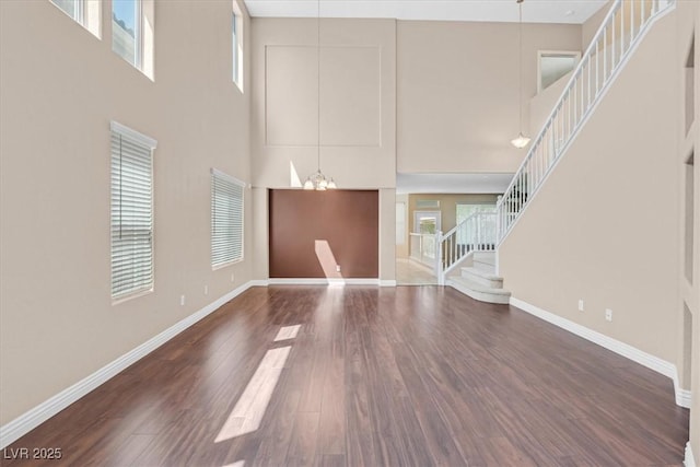 2864 Kinknockie Way, Henderson, NV 89044 - unfurnished living room with a towering ceiling, stairway, wood finished floors, baseboards, and a chandelier