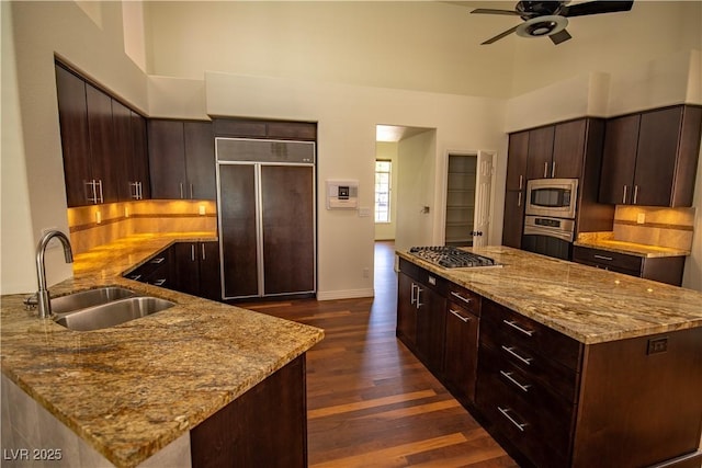 185 Camrose St, Henderson, NV 89074 - kitchen featuring a sink, built in appliances, ceiling fan, dark wood finished floors, and light stone counters