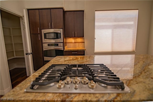 185 Camrose St, Henderson, NV 89074 - kitchen with appliances with stainless steel finishes, dark brown cabinetry, light stone countertops, tasteful backsplash, and wood finished floors