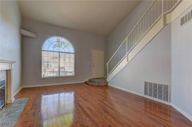 7968 Lisa Dawn Ave, Las Vegas, NV 89147 - unfurnished living room featuring wood finished floors, a tile fireplace, stairway, and baseboards