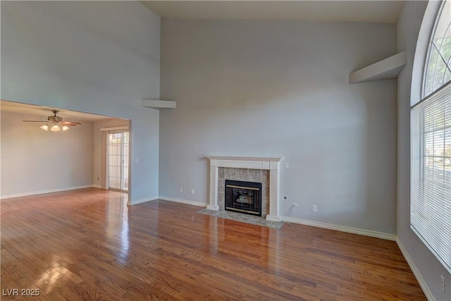 7968 Lisa Dawn Ave, Las Vegas, NV 89147 - unfurnished living room featuring a towering ceiling, a fireplace, wood finished floors, a ceiling fan, and baseboards