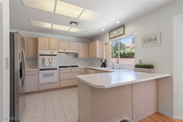 2925 Lotus Hill Dr, Las Vegas, NV 89134 - kitchen featuring white appliances, a sink, a peninsula, light brown cabinetry, and light countertops