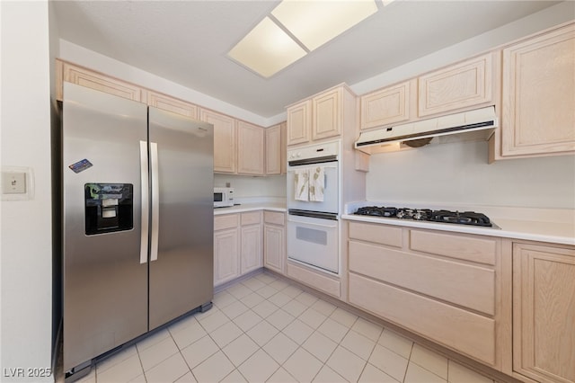 2925 Lotus Hill Dr, Las Vegas, NV 89134 - kitchen with white appliances, light brown cabinetry, under cabinet range hood, and light countertops