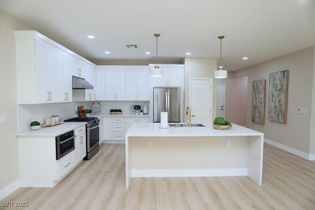 2623 Red Planet St, Henderson, NV 89044 - kitchen featuring appliances with stainless steel finishes, a sink, light wood-type flooring, a kitchen island with sink, and pendant lighting