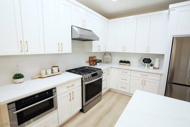 2623 Red Planet St, Henderson, NV 89044 - kitchen featuring appliances with stainless steel finishes, under cabinet range hood, light wood-type flooring, and white cabinetry