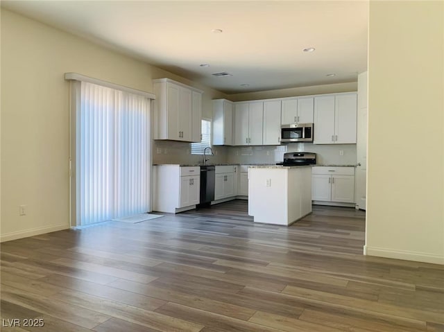 8793 Candelabra Ct, Las Vegas, NV 89148 - kitchen with stainless steel microwave, range, black dishwasher, white cabinetry, and dark wood-style flooring