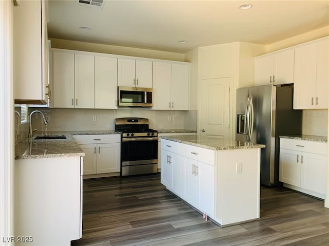 8793 Candelabra Ct, Las Vegas, NV 89148 - kitchen featuring appliances with stainless steel finishes, a sink, dark wood-type flooring, a center island, and white cabinets