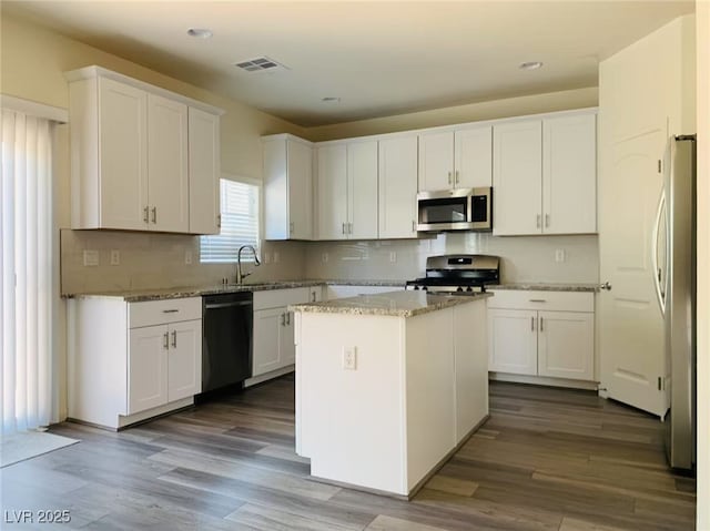 8793 Candelabra Ct, Las Vegas, NV 89148 - kitchen featuring stainless steel appliances, white cabinets, dark wood-style flooring, decorative backsplash, and recessed lighting