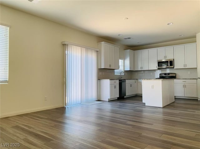 8793 Candelabra Ct, Las Vegas, NV 89148 - kitchen with stainless steel appliances, dark wood-style floors, white cabinets, a kitchen island, and baseboards