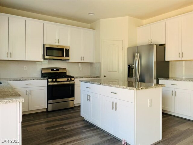 8793 Candelabra Ct, Las Vegas, NV 89148 - kitchen with appliances with stainless steel finishes, dark wood-type flooring, white cabinetry, a kitchen island, and recessed lighting