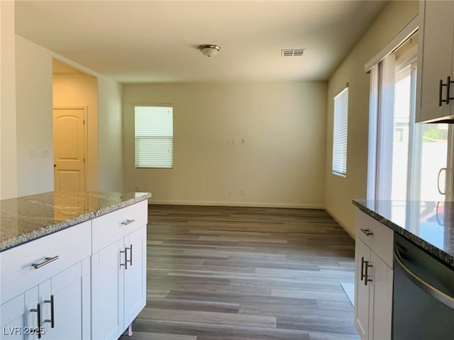 8793 Candelabra Ct, Las Vegas, NV 89148 - kitchen with stainless steel dishwasher, light wood finished floors, stone countertops, white cabinets, and baseboards
