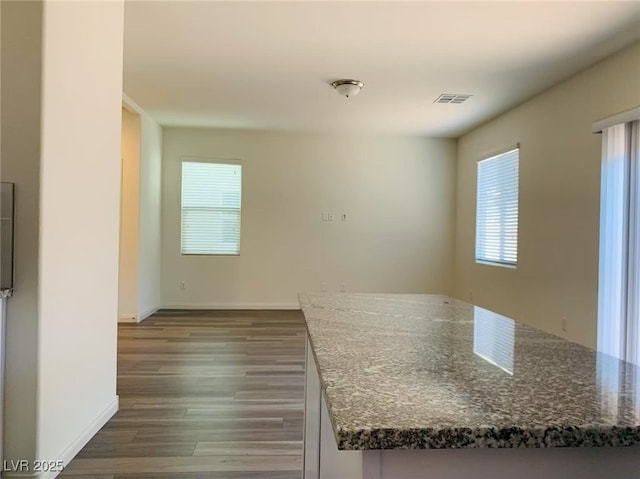 8793 Candelabra Ct, Las Vegas, NV 89148 - kitchen featuring dark wood-style flooring, dark stone counters, baseboards, and a kitchen island