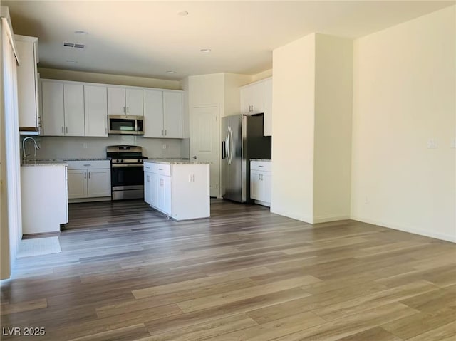 8793 Candelabra Ct, Las Vegas, NV 89148 - kitchen featuring stainless steel appliances, a kitchen island, white cabinets, light wood-type flooring, and recessed lighting