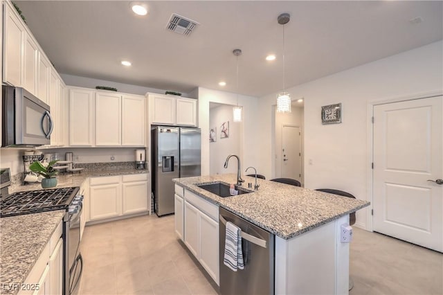 2114 Thelen Ave, North Las Vegas, NV 89086 - kitchen with appliances with stainless steel finishes, a sink, light stone counters, a kitchen island with sink, and recessed lighting