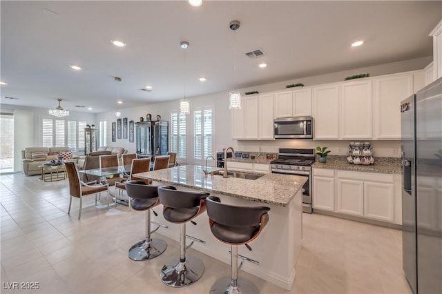 2114 Thelen Ave, North Las Vegas, NV 89086 - kitchen with stainless steel appliances, a sink, white cabinets, light stone counters, and open floor plan