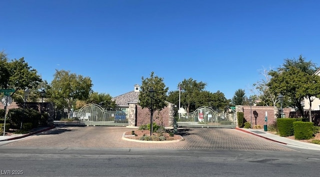 8218 Golden Flowers St, Las Vegas, NV 89139 - view of asphalt street featuring a gate, curbs, street lights, and a gated entry
