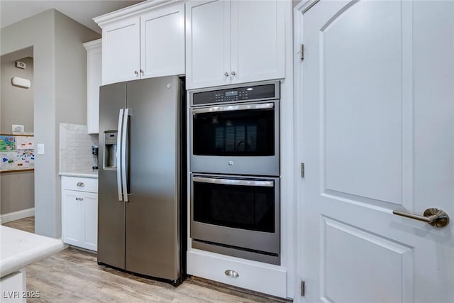 379 Mano Destra Ln, Henderson, NV 89011 - kitchen with appliances with stainless steel finishes, light wood finished floors, white cabinets, light countertops, and backsplash
