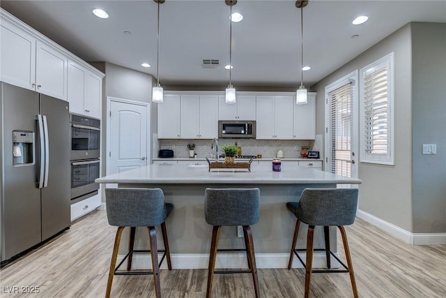 379 Mano Destra Ln, Henderson, NV 89011 - kitchen featuring stainless steel appliances, white cabinetry, tasteful backsplash, light countertops, and recessed lighting